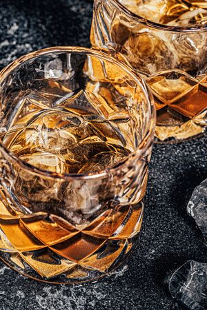 Whiskey with ice on a stone dark background.の写真素材