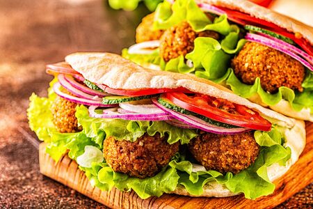 Falafel and fresh vegetables in pita bread on dark background.の写真素材