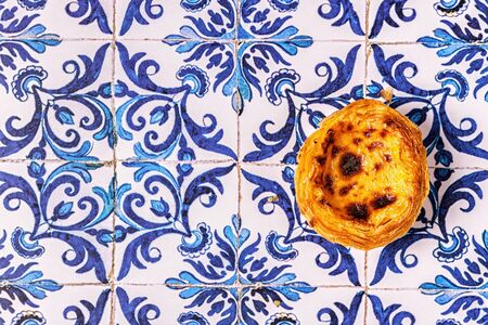 Egg tart, traditional Portuguese dessert, pastel de nata. Azulejo tile background.