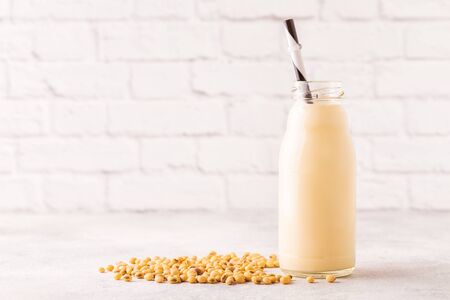 A bottle of soy milk and soy beans on a light background.の写真素材