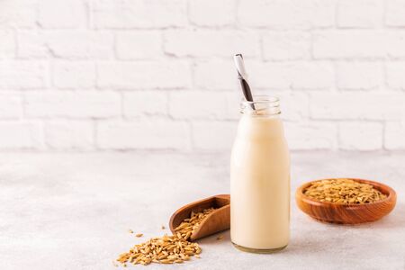 A bottle of oat milk and oats on a light background.の写真素材