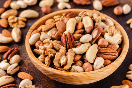 Various Nuts in wooden bowl on dark background.の素材 [FY310157692590]