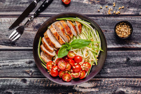 Fried chicken fillet and fresh vegetable salad of tomatoes, zucchini and pine nuts. Chicken meat salad. Healthy food. Ketogenic diet.の写真素材