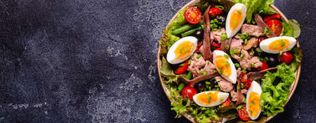 French salad Nicoise with tuna, eggs, green beans, tomatoes, olives, lettuce and anchovies.の写真素材