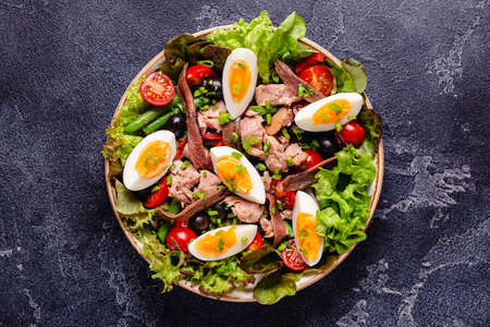 French salad Nicoise with tuna, eggs, green beans, tomatoes, olives, lettuce and anchovies.の写真素材