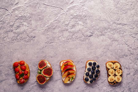 Homemade summer toast with cream cheese, nut butter and fruits and berries, top view.の写真素材