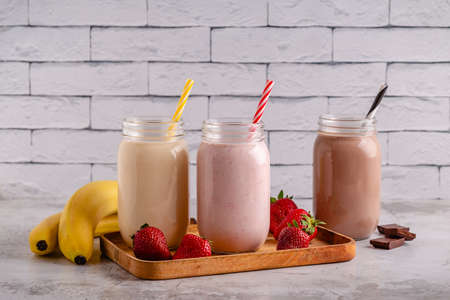 Set of strawberry banana and chocolate milkshakes in the glass jarsの写真素材