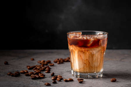 Ice coffee in a glass with cream poured over. Cold summer drink.