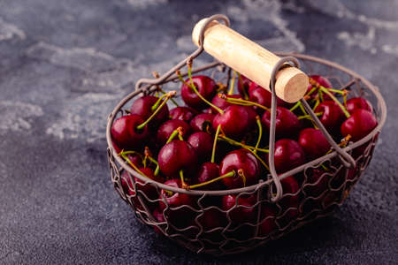 Fresh sweet red cherries in the basket on dark background, selective focusの写真素材