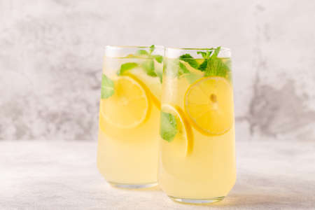 Lemonade with lemon, mint and ice cubes in glass, selective focus