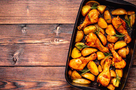 Roasted chicken legs with potatoes and rosemary. Top view.