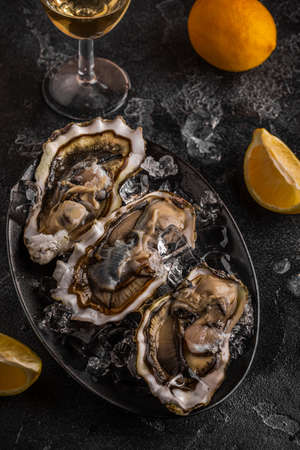 Fresh oysters close-up on ice served with lemon and wine. Healthy seafood, gourmet food.の写真素材