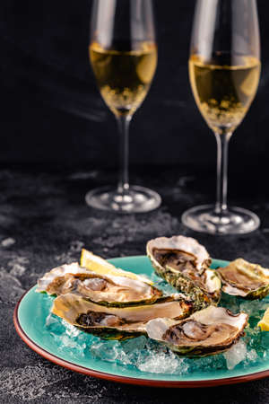 Opened fresh oysters on a blue plate, served with lemon and ice.の写真素材