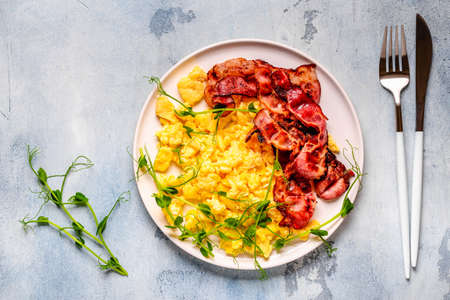 Traditional breakfast scrambled eggs with fried bacon. Top view.の写真素材