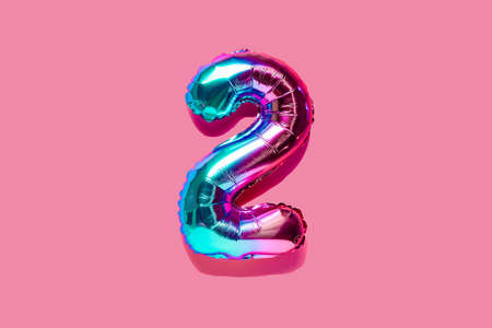 Rainbow foil balloon number, digit two . top view. Colored numeral on pink background.の写真素材