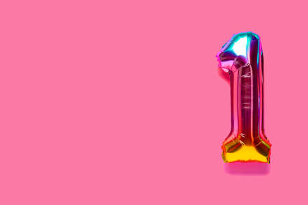 Rainbow foil balloon number, digit one. top view. Colored numeral on pink background.の写真素材