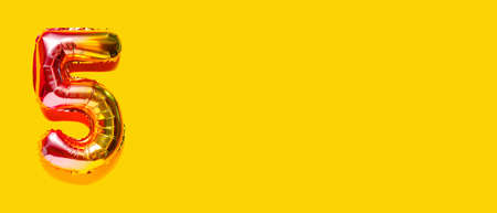 Rainbow foil balloon number, digit five. top view. Colored numeral on yellow background.
