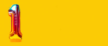 Rainbow foil balloon number, digit one. top view. Colored numeral on yellow background.
