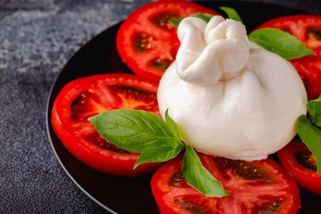 Caprese salad with tomatoes, burrata cheese and basil. dark background.の写真素材