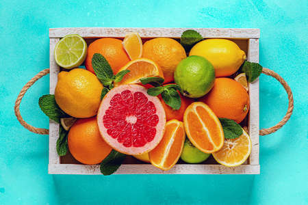 Fresh citrus fruits with leaves: lemons, oranges, mandarins, grapefruit, lime in wooden box, top...