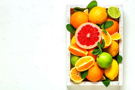 Fresh citrus fruits with leaves: lemons, oranges, mandarins, grapefruit, lime in wooden box, top view.の写真素材
