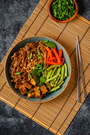 Soba noodles with vegetables and fried tofu in a bowl. Top view.の写真素材