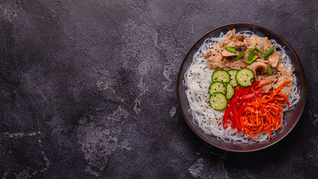 Bowl of rice noodles with vegan soy meat and vegetables on dark background, top viewの写真素材