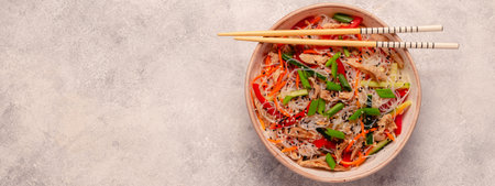 Bowl of rice noodles with vegan meat and vegetables on light background, top viewの写真素材