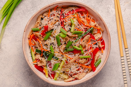 Bowl of rice noodles with vegan soy meat and vegetables on light background, top viewの写真素材