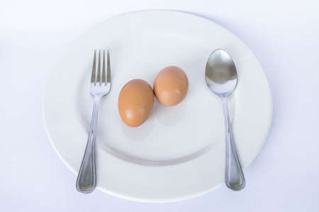 eggs, fork and spoon in a white plateの写真素材