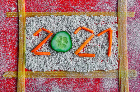 Banner 2021 from spaghetti, cucumer, carrot and rice on red background with flour