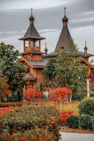 Wooden Orthodox Church with autumn foliage on the foreground