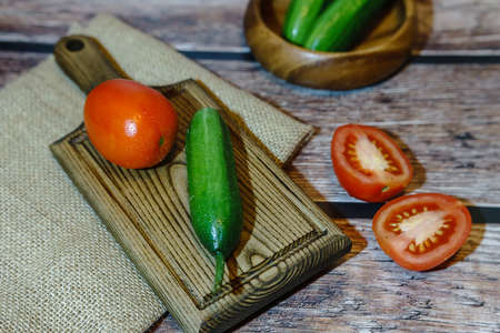 High angle view of cucumbers and tomatoes on a wooden backgroundの写真素材