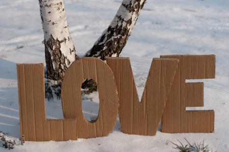 Letters L,O,V,E made from cardboard, placin on the snow between two human trailsの写真素材