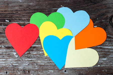 Different color paper hearts on an old woodの写真素材