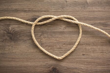 Heart shape made of rope on a wooden backgroundの写真素材