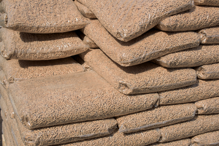Heap with wooden pellets in bags for home heating