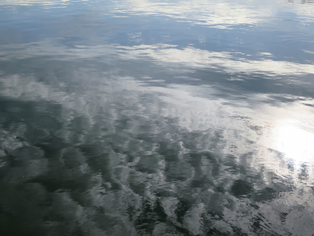 Shades of grey color reflection on fresh water surface on a cloudy dayの写真素材