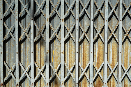 Rusty grey Steel folding entry door detail background with casted shadow, Phuket, Thailandの写真素材