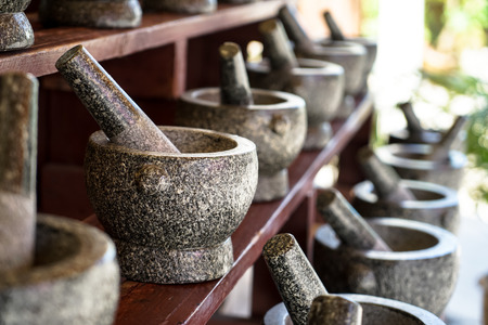 Sets of mortar and pestle in grey and black color granite stone arranging on wooden shelf for sale in local market, Thailandの写真素材