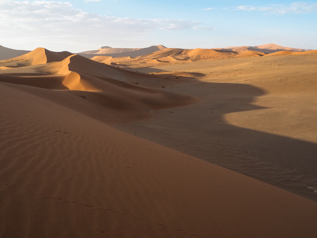 Beautiful natural curved ridge line and wind blow pattern of rusty red sand dune with soft shadow on vast desert landscape, Sossus, Namib desert, Namibiaの写真素材