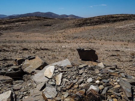 Natural rock mountain dried dusty landscape ground of Namib desert with splitting shale pieces, other stone and desert plant, Namibiaの写真素材