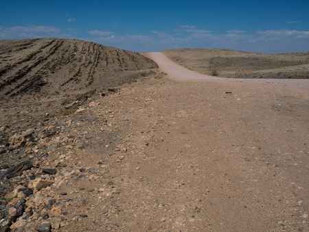 Copyspace of road trip through dried dusty rock mountain  landscape ground of Namib desert with splitting stone and blue sky, Namibiaの写真素材