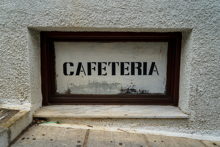 Street side rustic vintage cafeteria print signage on white background in dark wooden frame on white texture concrete wall, Greeceの写真素材