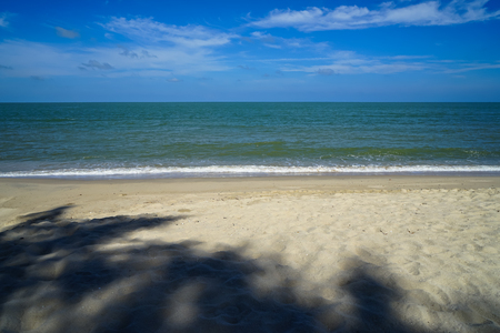Calm soft foam sea wave on white sandy beach with tree shade and blue sky background, Samila beach, Songkhla, Thailandの写真素材