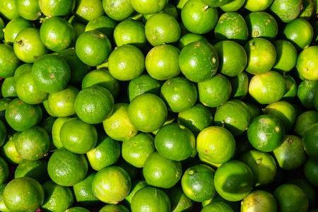 Pile of fresh rounded organic lime fruit background in bright yellow and green color selling in...