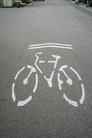 Bicycle direction signage, environmental friendly symbol, in white on urban grey asphalt street...