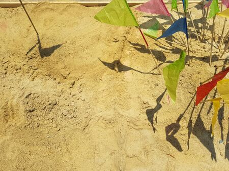 Colorful triangle paper flags stick on brown sand background with copyspace for making traditional sand pagoda on Sonkran festival, Bangkok, Thailandの写真素材