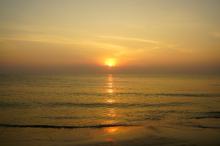Beautiful panoramic morning sunrise seaview with wave water reflection through sand beach, shades of soft wide orange color sky and abstract cloud background, Hua Hin, Thailandの写真素材