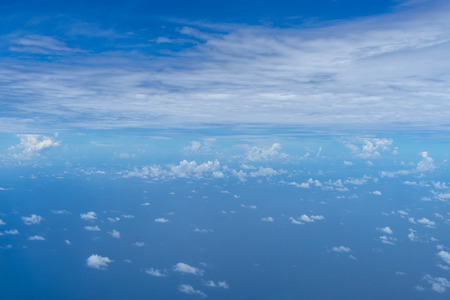 View of small abstract white cloud with bright blue sky horizon and vast sea ocean background from above flying airplane window, Phuketの写真素材